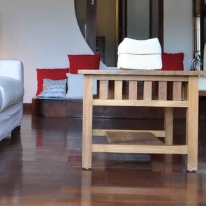 Couchtisch Atelier aus Massivholz Teak mit einer Ablageflaeche im unteren Bereich. Der Massivholz Sofa Tisch ist an der Zarge mit eleganter Slated Optik verziert, Beistelltisch im Kolonialstil, hier in der Abbildung in der MOEBEL KOLONIE Farbe Roh und unbehandelt, Wohnzimmer Moebel Muenchen vom Schreiner in Handarbeit auf Mass gefertigt