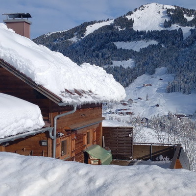 Panoramabild Ferienhaus mit Holzschindeln im Winter. Chalet in den Alpen mit Schnee und Weitblick